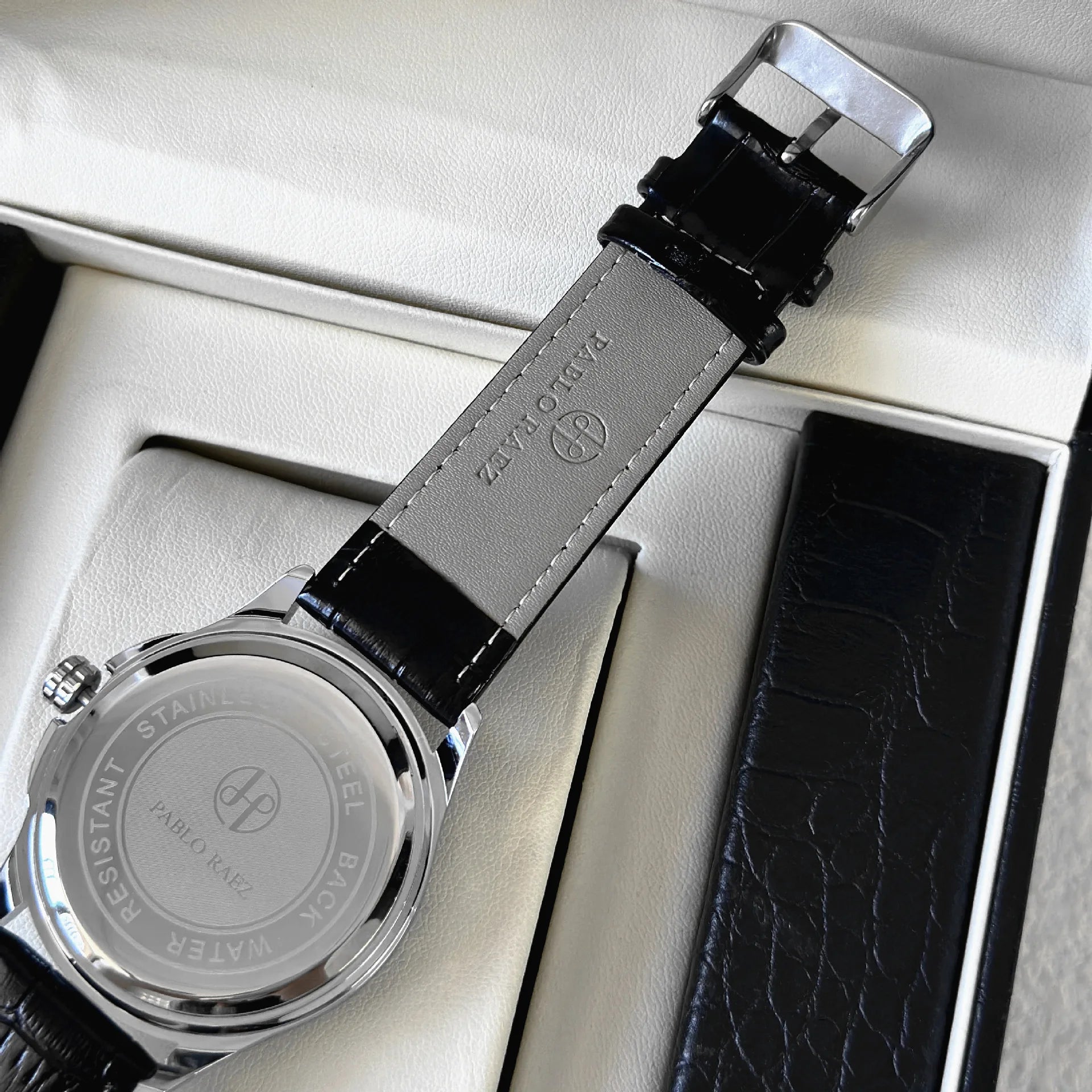 Watch with black leather strap on a white surface