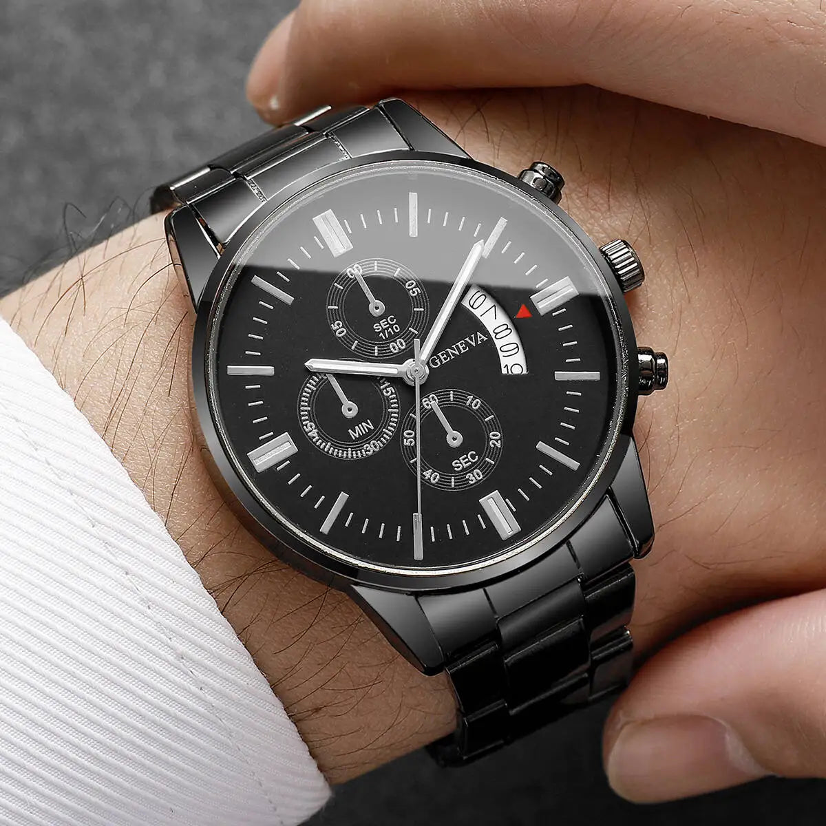 Black wristwatch with silver strap on a person's wrist against a dark background