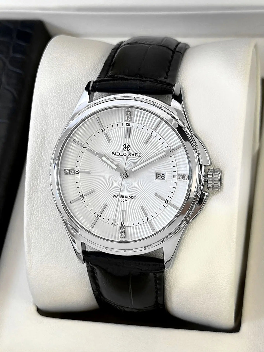 Silver watch with black leather strap on a white cushion