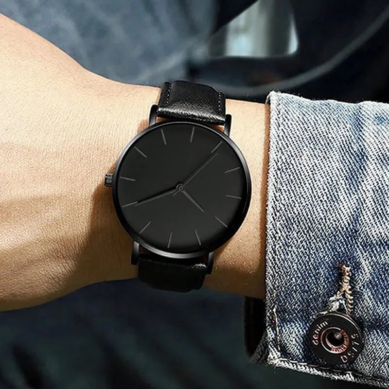 Black wristwatch on a person's wrist with a denim sleeve.