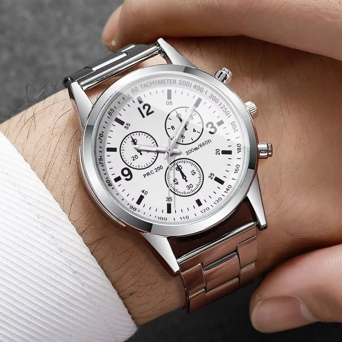 Silver wristwatch with a detailed face on a person's wrist.