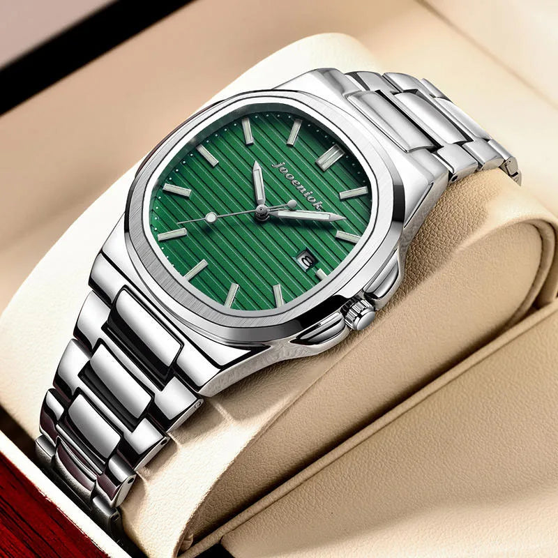 Silver watch with a green face on a beige surface