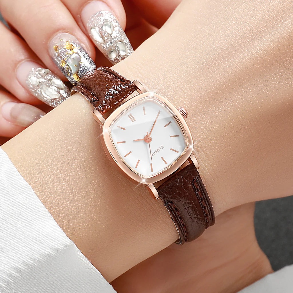 Wristwatch with brown leather strap and rose gold case on a wrist with decorative nails.