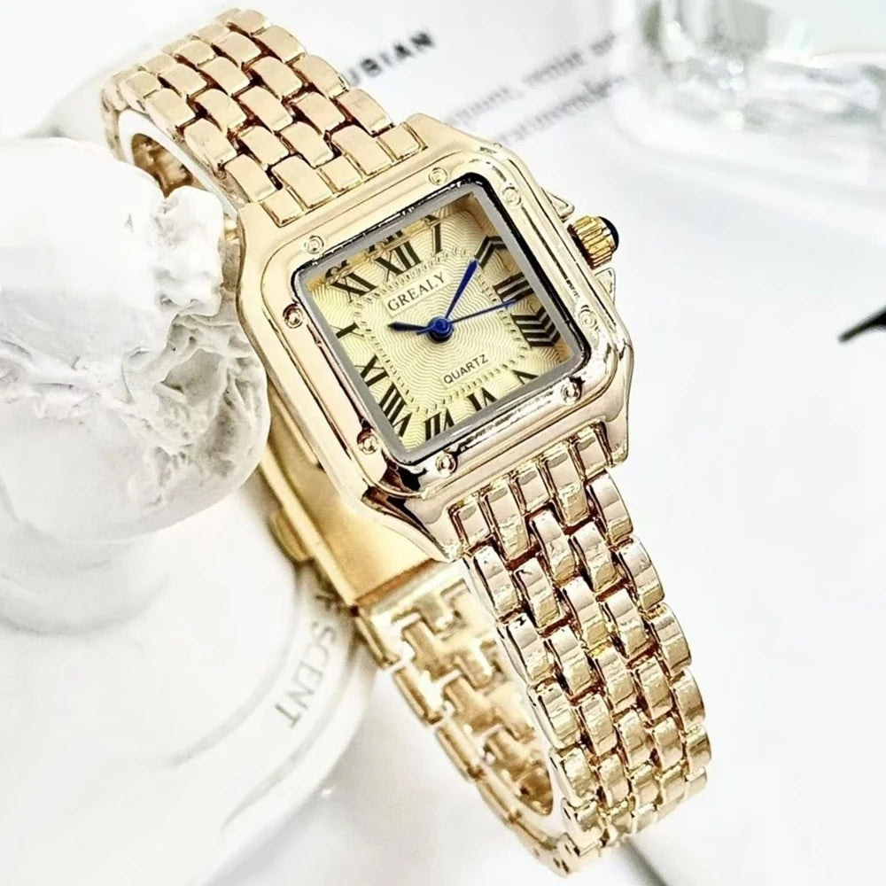Gold wristwatch with a decorative band on a white background