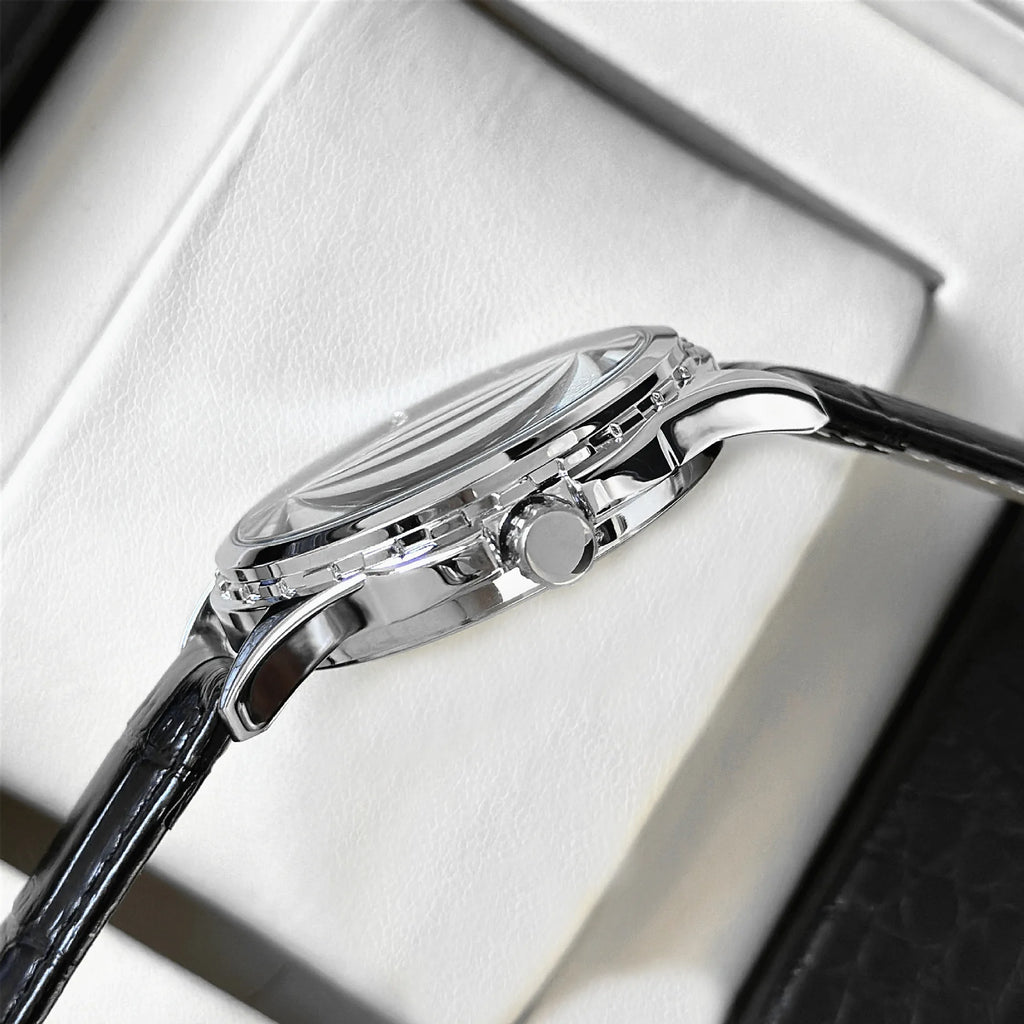 Close-up of a silver watch with black strap on a white cushion