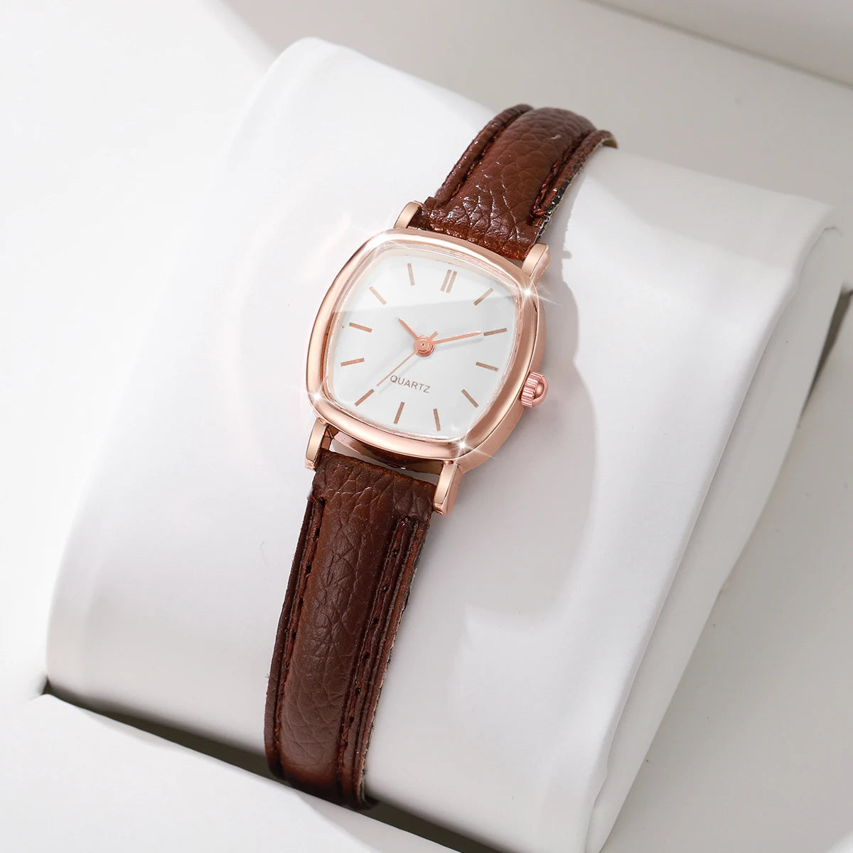 Wristwatch with brown leather strap and rose gold case on a white cushion
