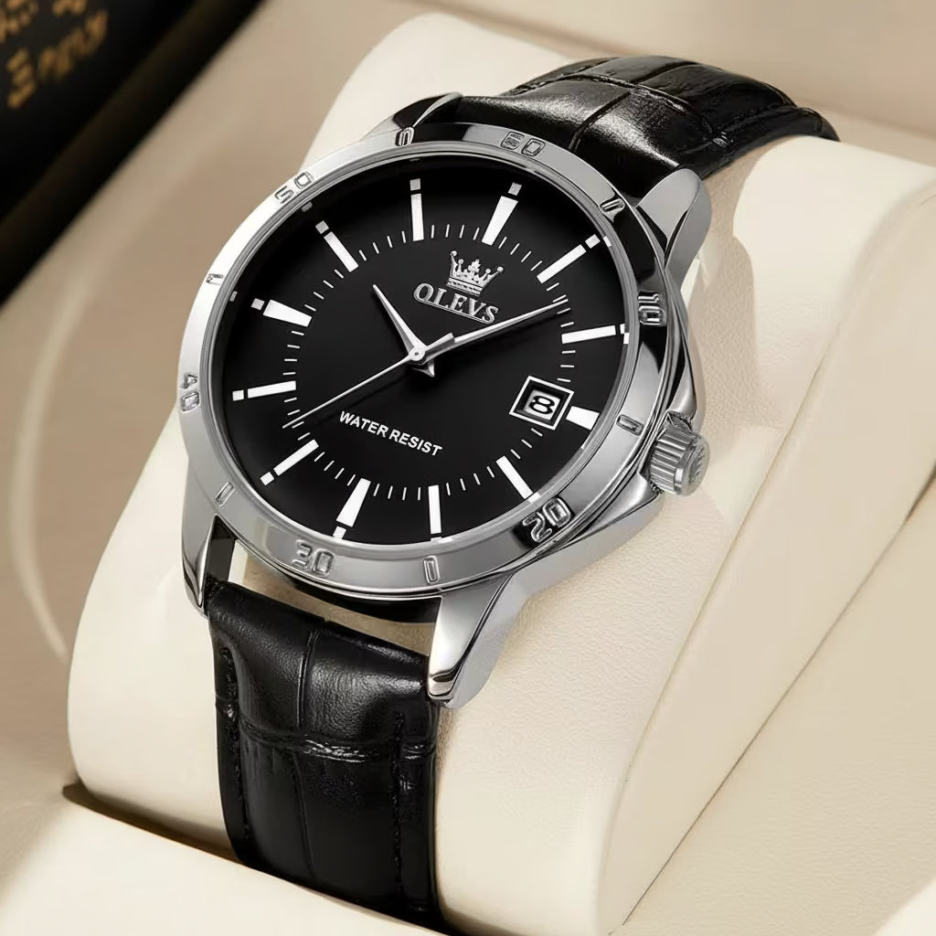 Black wristwatch with silver case and black leather strap on a beige surface